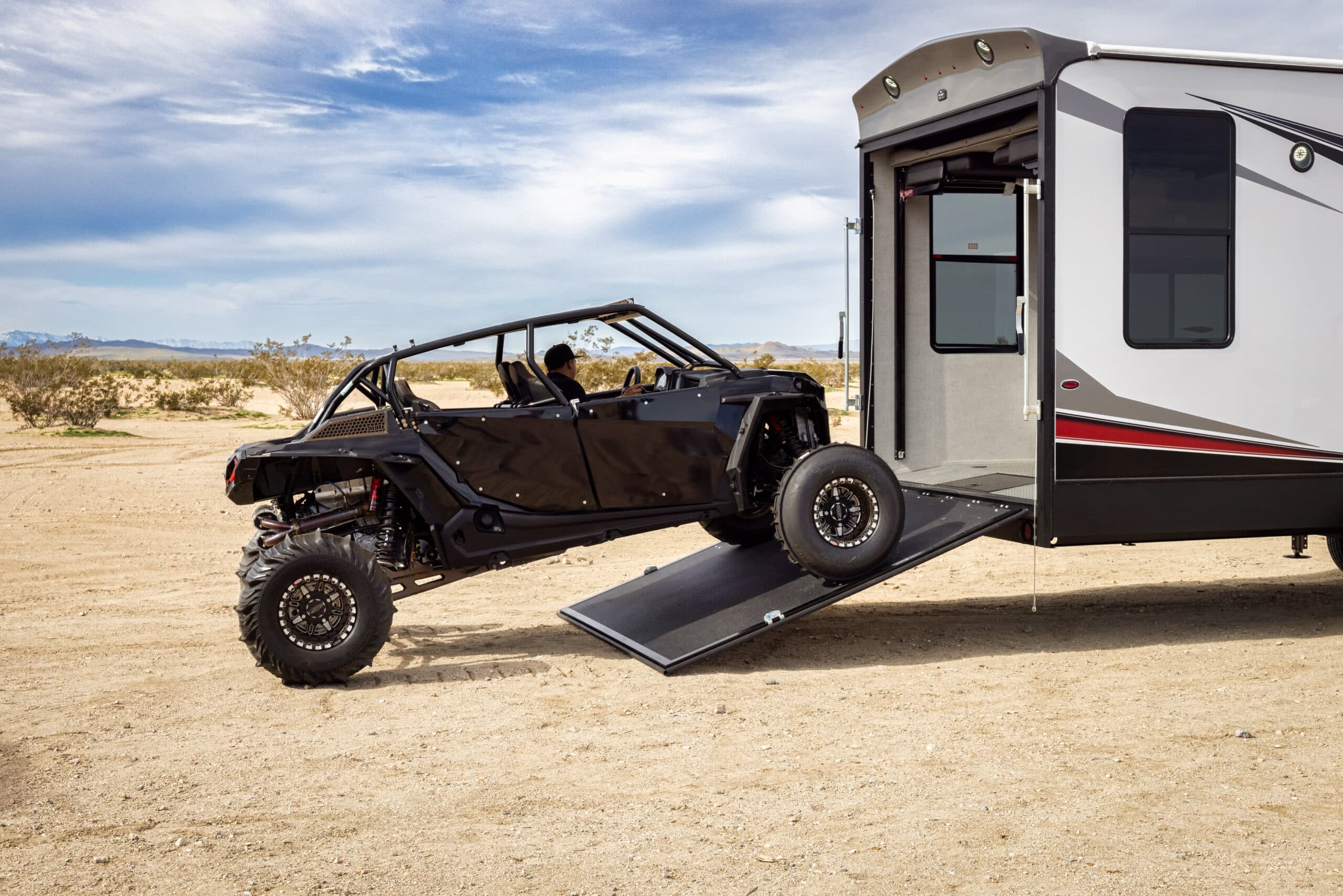 UTV being loaded into an RV via rear ramp in the desert
